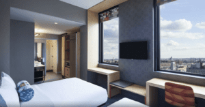 A hotel room with a large window and a flat screen tv.