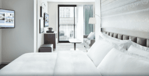 A hotel room with white sheets and pillows.