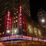 The radio city building is lit up at night.